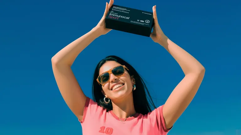 Person in pink holding an Immunocal box against a blue sky