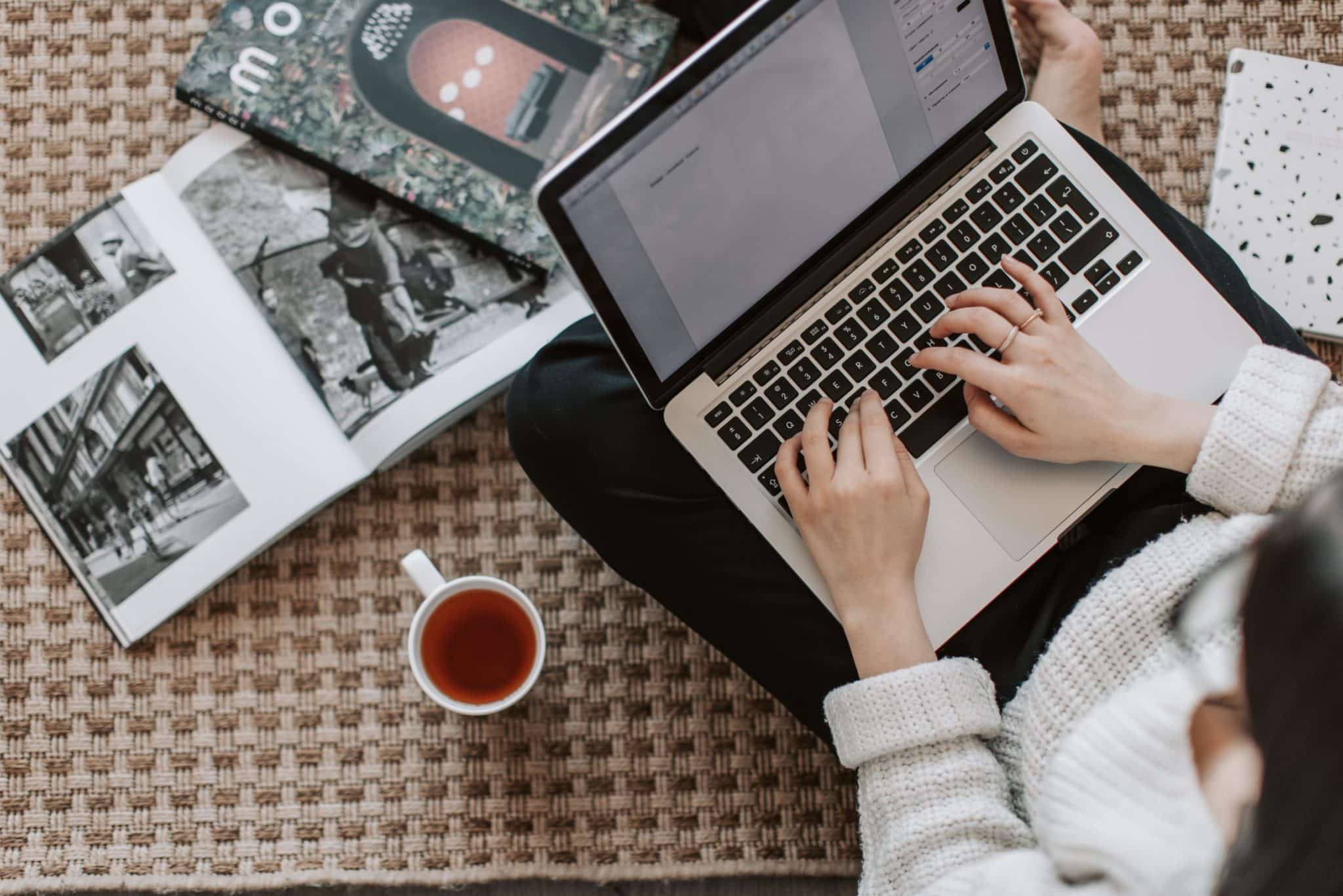 stock-photo-of-woman-referring-to-magazines-while-working-on-laptop