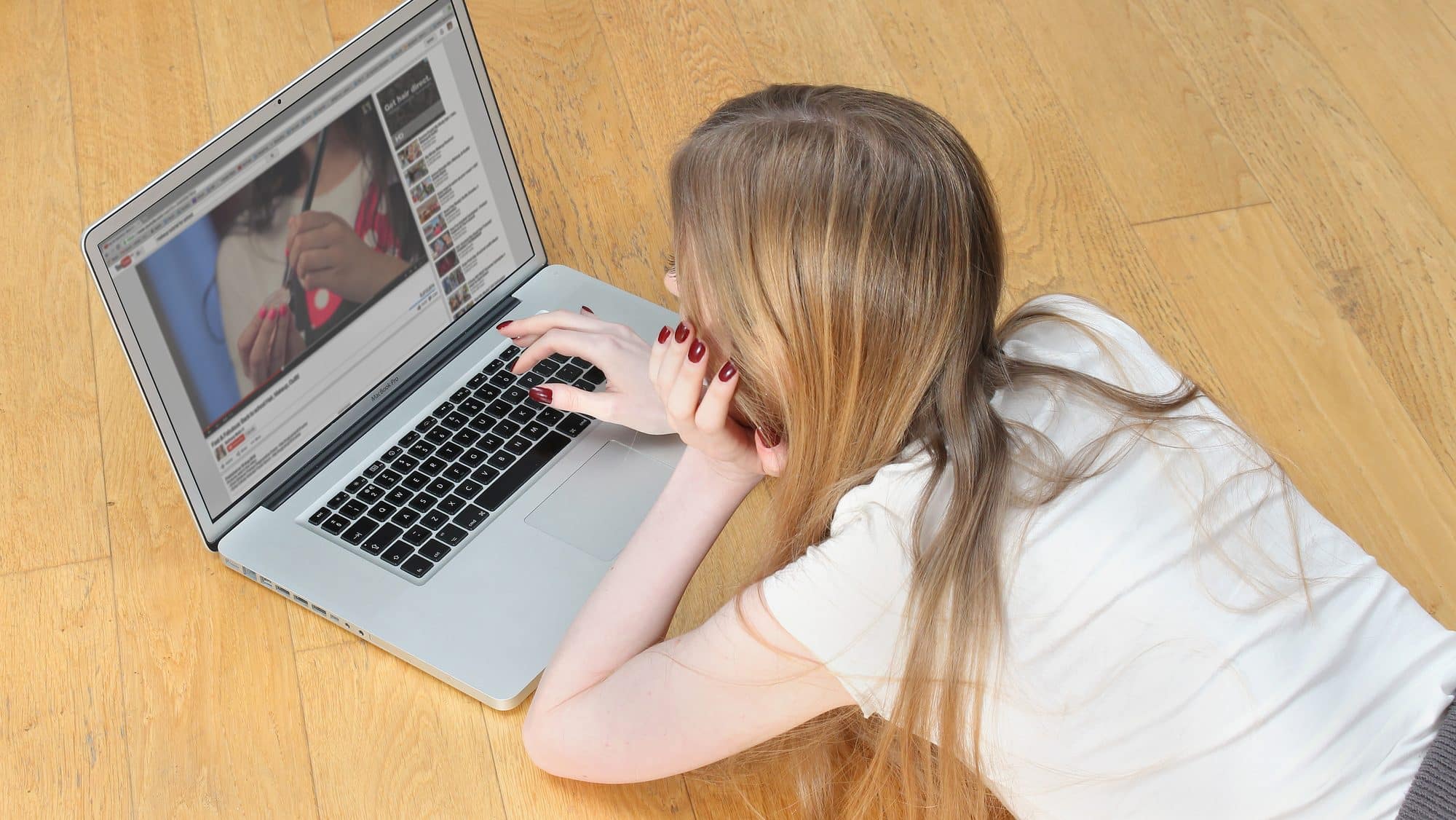 Belgrade, Serbia - November 27, 2014: Teenage girl laying on the floor in front of laptop looking at YouTube videos searching for make up tutorials