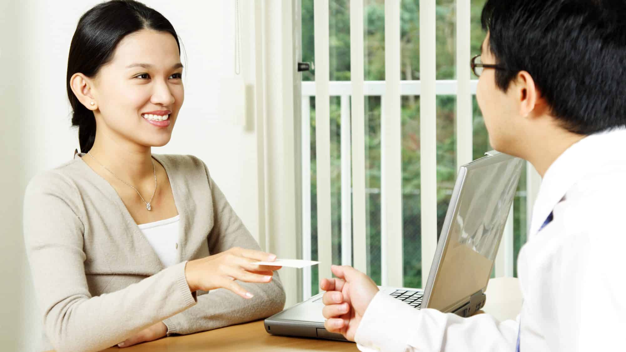 A businesswoman handing out a business card to a businessman