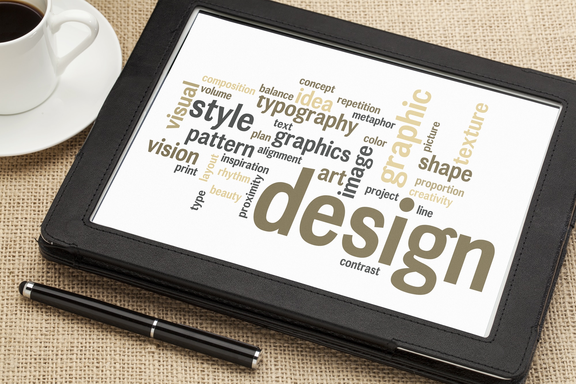 cloud of words or tags related to graphic design  on a  digital tablet with a cup of coffee