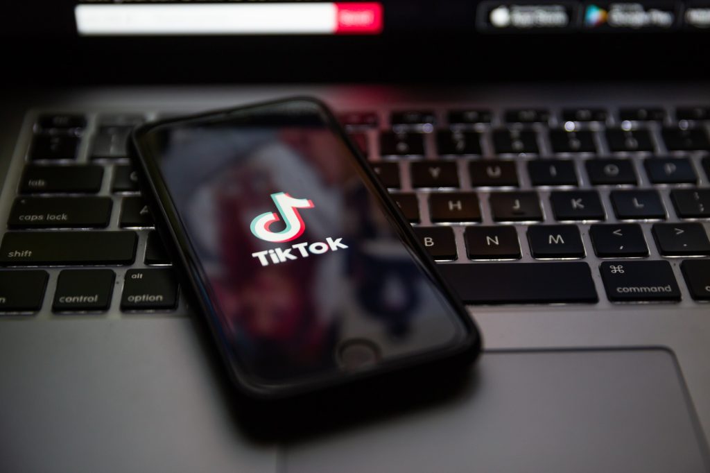 TERNOPIL, UKRAINE - JANUARY 11, 2020: TikTok brand logo on the screen of Apple iPhone 7 in the evening. Keyboard of Macbook Pro in background. TikTok is a popular social media network.