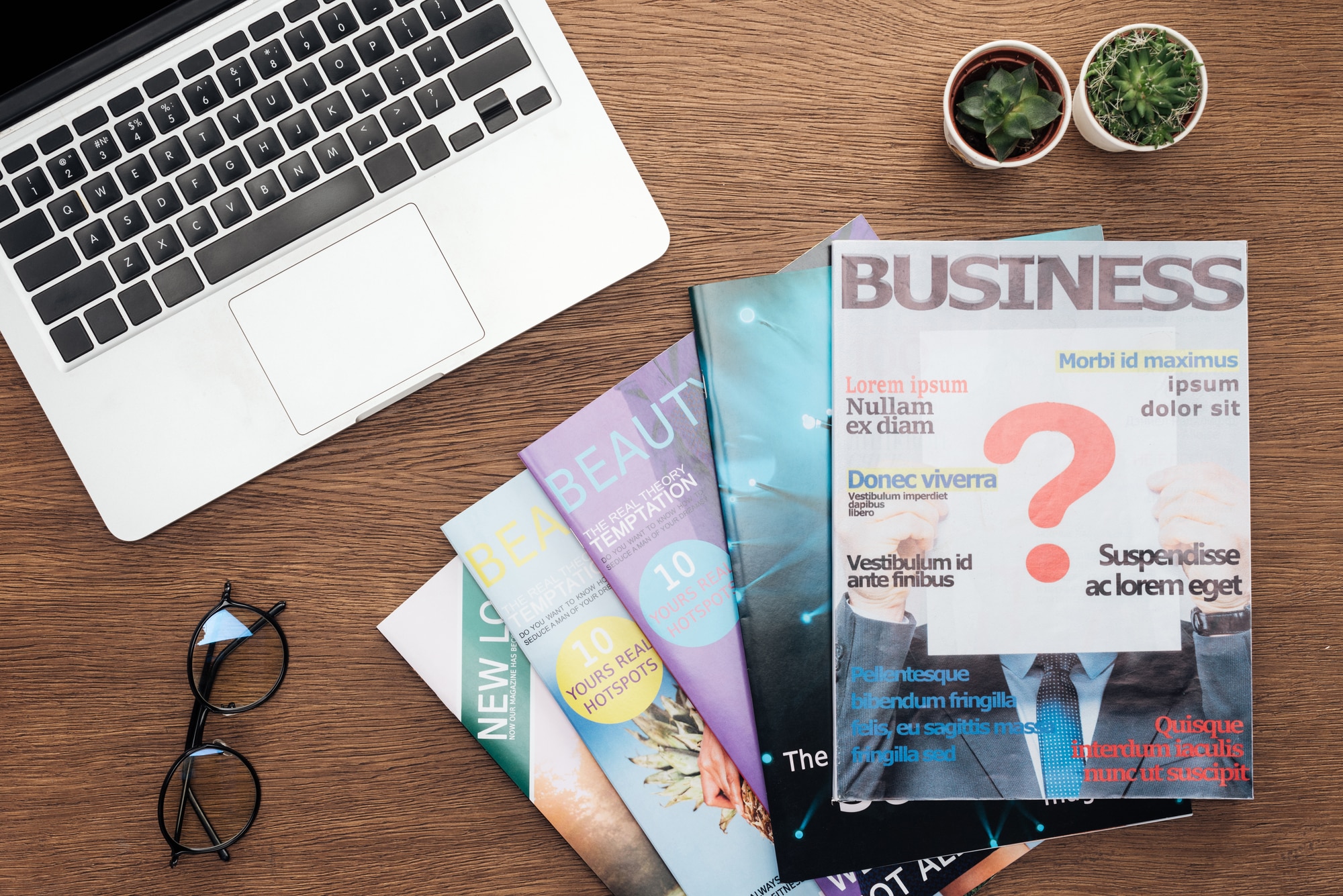 Stock-image-of-stack-of-business-magazines-next-to-laptop