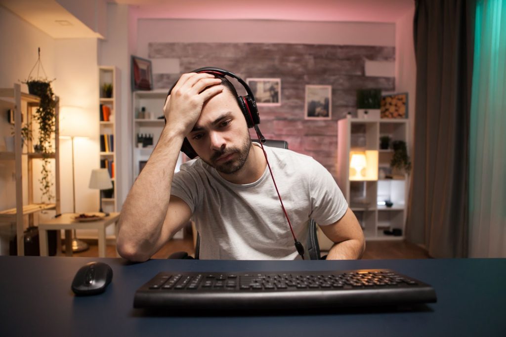 Mna sitting with his head in his hands, looking at a keyboard on a table
