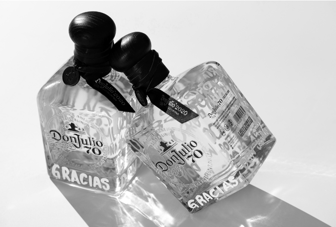 Two clear glass bottles with black tops leaning against each other